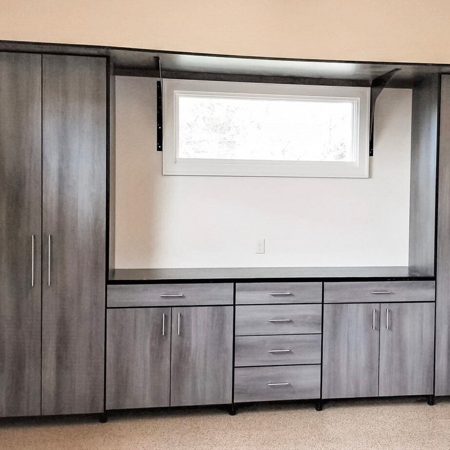 The closet butler custom garage with grey wood finish inset storage area.
