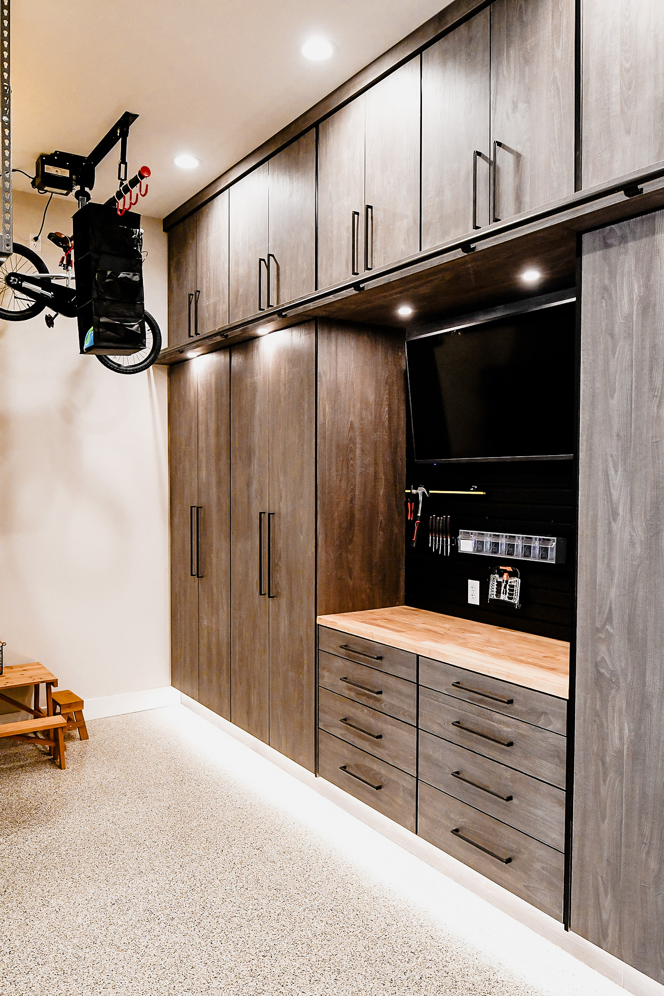 Custom Garage Cabinets by The Closet Butler Complete garage storage system with custom cabinetry, slat walls, and overhead storage.