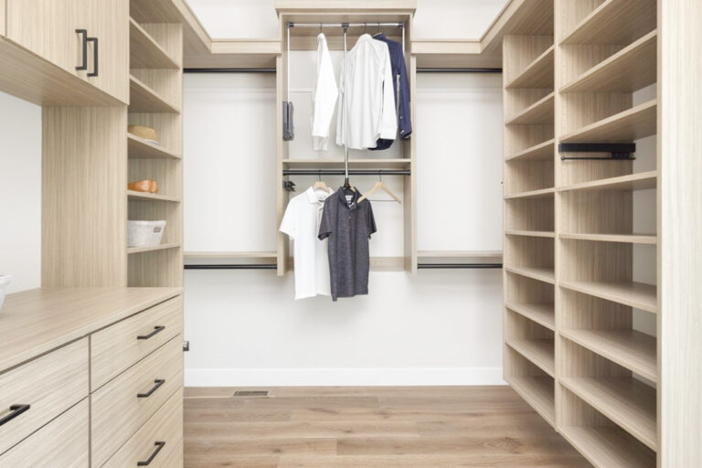 Custom walk in closet featuring warm neutral wood finishes, empty shelves, and stylish hanging spaces for clothing and accessories.