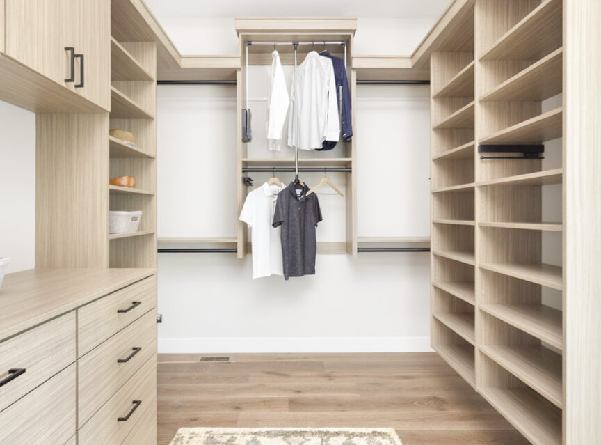 Custom walk in closet featuring warm neutral wood finishes, empty shelves, and stylish hanging spaces for clothing and accessories.
