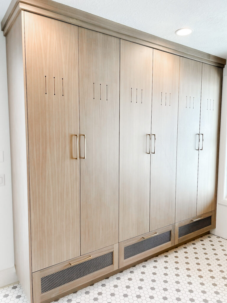 Luxury custom-designed mudroom by The Closet Butler with built-in cabinets, bench seating, and coat hooks.