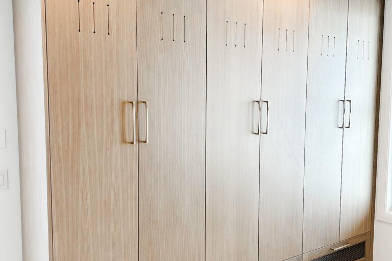 Luxury custom-designed mudroom by The Closet Butler with built-in cabinets, bench seating, and coat hooks.