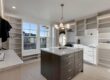 Bright walk-in closet with white built-in shelves, a dark wood island with a marble top, and a round mirror under a modern chandelier.