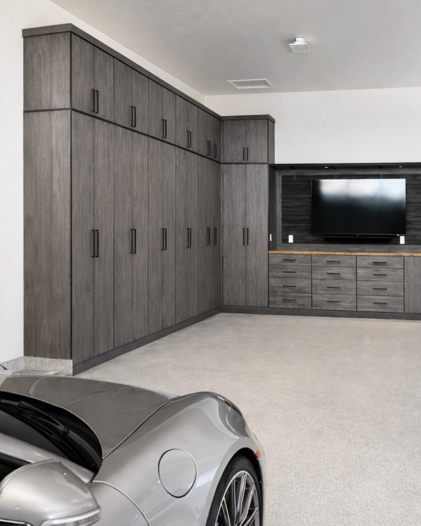 Modern garage with tall dark wood cabinets along the left wall and a silver sports car in the foreground.