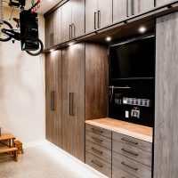 Complete garage storage system with custom cabinetry, slat walls, and overhead storage.